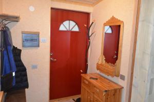 La salle de bains est pourvue d'une porte rouge et d'un miroir. dans l'établissement Butas su sodu saulėtoje verandoje Juodkrantėje, prie Ievos Kalno, à Juodkrantė