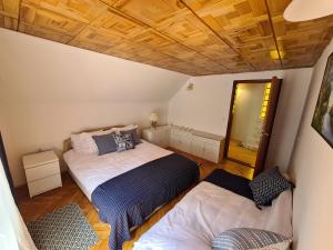 een slaapkamer met 2 bedden en een houten plafond bij Planinska kuća Koreni in Jasikovice