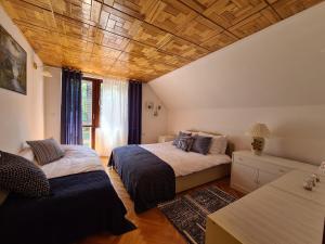 2 bedden in een kamer met houten plafonds bij Planinska kuća Koreni in Jasikovice