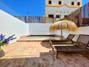 eine Terrasse mit 2 Stühlen, einem Sonnenschirm und einem Pool in der Unterkunft Alvor Bela Vista II in Alvor