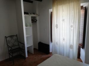 1 dormitorio con cortina blanca y silla en Apartamentos Rurales Lanteira en Lanteira
