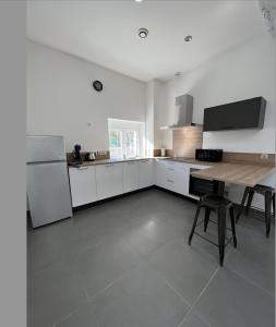 a white kitchen with a table and a refrigerator at LE LOFT - 70m2 T3 Cronenbourg 6 pers in Strasbourg