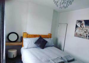 a bedroom with a white bed with a wooden headboard at The Stone House II in Nottingham