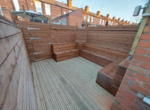 a patio with wooden benches and a brick wall at The Stone House II in Nottingham