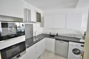 a kitchen with white cabinets and a washer and dryer at Flat in Juan in Antibes