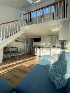 a living room with a blue couch and a kitchen at Whispering Waves in Porthtowan @ Cornwall Coastal Holidays in Porthtowan