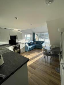 a kitchen and living room with a couch and a table at Whispering Waves in Porthtowan @ Cornwall Coastal Holidays in Porthtowan
