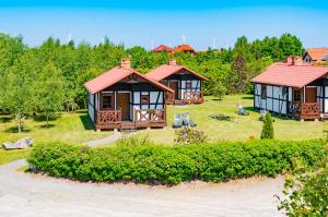 a small house with a red roof on a yard at Domki Dzika Róża in Darłowo