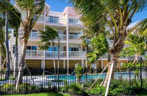 a building with palm trees and a swimming pool at Grassy Flats Resort & Beach Club in Marathon