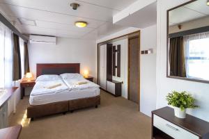 a bedroom with a bed and two tables and a mirror at Botel Vodnik in Prague