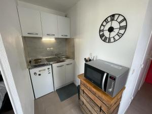 a kitchen with a microwave and a clock on the wall at Adara YourHostHelper in Caen