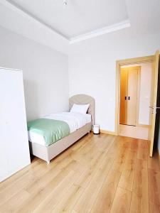 a white bedroom with a bed and a wooden floor at Garden Grandresidence in Basaksehir
