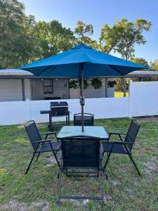 a table and chairs with a blue umbrella at House of Manatees-Entire house with yard, fire pit, dog friendly in Crystal River