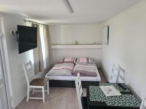Una pequeña habitación con una cama, una mesa y sillas. en Melanie apartman 2, en Veľký Meder