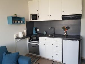 una pequeña cocina con armarios blancos y un sofá azul en Appartement Royan, 200 m de la PLAGE en Royan