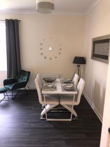 uma sala de jantar com uma mesa e um relógio na parede em Vogue Apartments em Glasgow