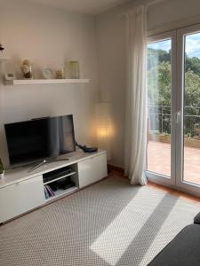 uma sala de estar com uma televisão e uma porta de vidro deslizante em Rascassa em Llafranc