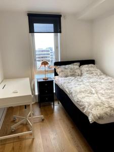 a bedroom with a bed and a desk and a window at Royal Skir apartment sea view in Tromsø