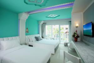 1 dormitorio azul con 2 camas y TV en The Verandah - SHA Extra Plus, en Ao Nang Beach
