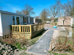 a house with a wooden deck next to a yard at BJ Chalets - Robbengat 68 - Gezellige, kindvriendelijke chalet op vakantiepark Lauwersoog! Vroege incheck! in Lauwersoog