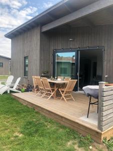 a wooden deck with a table and chairs on it at Gotland Tofta, Stuga med superläge! Havsutsikt på Tofta strand mindre än 10 minuter till en av Sveriges högst rankade golfbana! in Visby