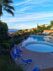 - une piscine avec des chaises longues bleues et l'océan dans l'établissement Rousseau, à Théoule-sur-Mer