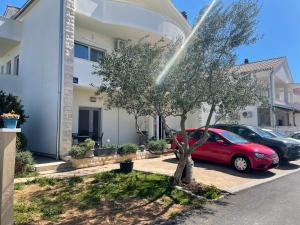 um carro vermelho estacionado ao lado de uma árvore em frente a uma casa em Apartment Maras em Vodice