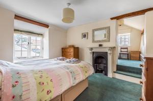 een slaapkamer met een bed en een open haard bij Heydons House - Lovely Seaside Cottage in Sidmouth