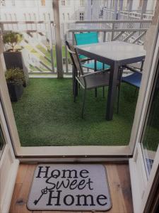 a balcony with a table and a sign that says home sweet home at Charmant Studio en duplex esprit loft avec balcon vue mer, et piscine extérieure in Le Croisic