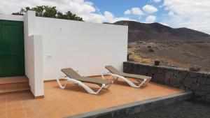 zwei Stühle auf einer Terrasse mit einer Wand in der Unterkunft Omae Papagayo in Playa Blanca