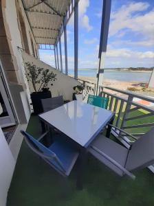 een tafel en stoelen met uitzicht op het strand bij Charmant Studio en duplex esprit loft avec balcon vue mer, et piscine extérieure in Le Croisic