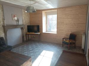 ein Wohnzimmer mit einem Kamin und einem TV in der Unterkunft Gite Auvraysien 10p in La Forêt-Auvray