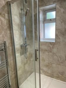 a shower with a glass door and a window at Travel Legend Stays 1 or 2 bedroom place with Hot Tub in Farnham Royal