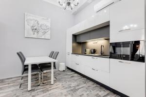 cocina con armarios blancos, mesa y sillas en Apartment Thunovská 10 en Praga