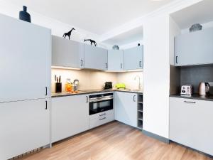 a white kitchen with white cabinets and a wooden floor at LivinParis - Luxury 2 Bedrooms Centre Pompidou in Paris +11 photos