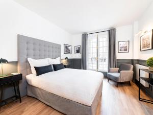 - une chambre avec un grand lit blanc et une chaise dans l'établissement LivinParis - Luxury 2 Bedrooms Centre Pompidou, à Paris