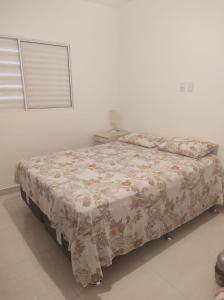 a bedroom with a bed with a flowered blanket at Acomodação corporativa: casa residencial recém-construída in Itatiba