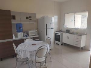 a kitchen with a table and chairs and a refrigerator at Acomodação corporativa: casa residencial recém-construída in Itatiba