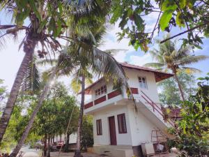 a white house with palm trees in front of it at Achayans Homestay Mararikulam in Mararikulam