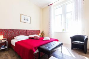 um quarto com uma cama com um cobertor vermelho e uma cadeira em Lady of Health Apartments em Zadar