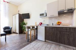 kuchnia z białymi szafkami i stołem z stołkami w obiekcie Lady of Health Apartments w mieście Zadar