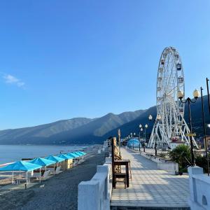 a beach with a ferris wheel and a roller coaster at Мини-отель New Gagra in Gagra