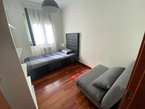 een slaapkamer met een bed en een bank erin bij Apartamento tranquilo Vielha Centro con Parking Gratuito in Vielha