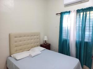 a bedroom with a white bed with blue curtains at Turnbull's Apart Hotel in Consuelo