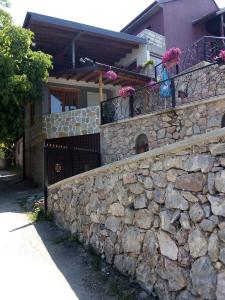 a stone wall in front of a house with flowers at Guest House Stevovski in Ohrid