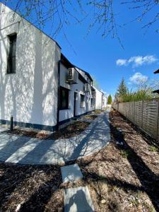 a white building with a fence next to a sidewalk at Silver Residence Zamárdi By BLTN in Zamárdi