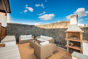 patio z kominkiem i kamienną ścianą w obiekcie Villa Vista Rey - 6 Bedroom - Heated Pool - Amazing Views - Pool Table - Vista Lobos - Playa Blanca w mieście Playa Blanca
