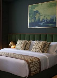 a large bed with a green headboard and pillows at Grand Opera Hotel in Kutaisi