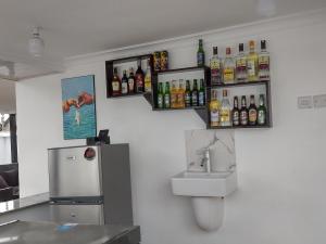 a kitchen with a sink and a counter with bottles on the wall at Mkamiti Villa - Airport Villa with Free Shuttle in Dar es Salaam