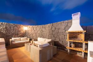 patio z wiklinowymi krzesłami i ceglaną ścianą w obiekcie Villa Vista Rey - 6 Bedroom - Heated Pool - Amazing Views - Pool Table - Vista Lobos - Playa Blanca w mieście Playa Blanca +23 zdjęcia